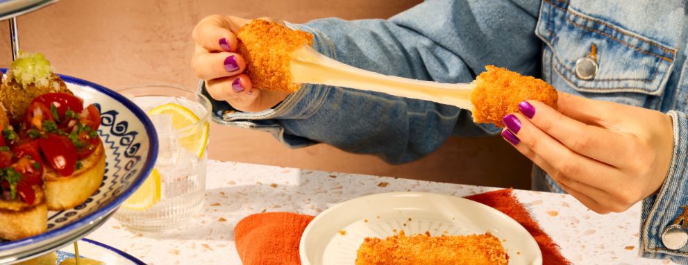 Cheese pull on a mozzarella stick during afternoon tea